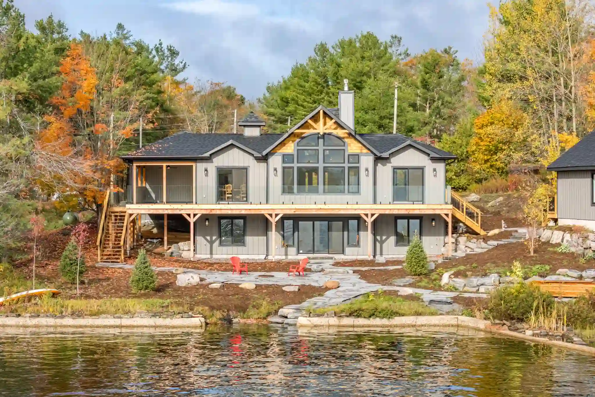 Grey waterfront cottage with timber gable and fire pit patio in fall, an example listing worth verifying an agent's credentials before hiring them to sell